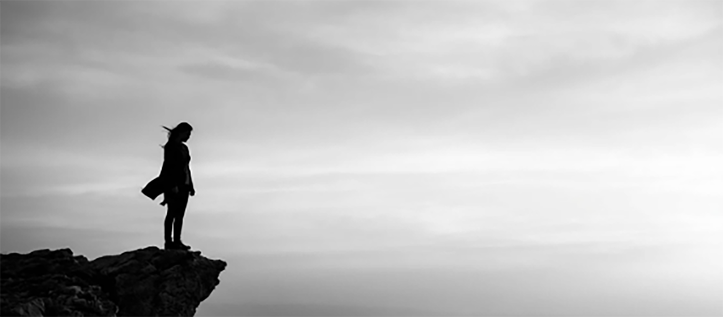 A woman stands on the edge of a cliff